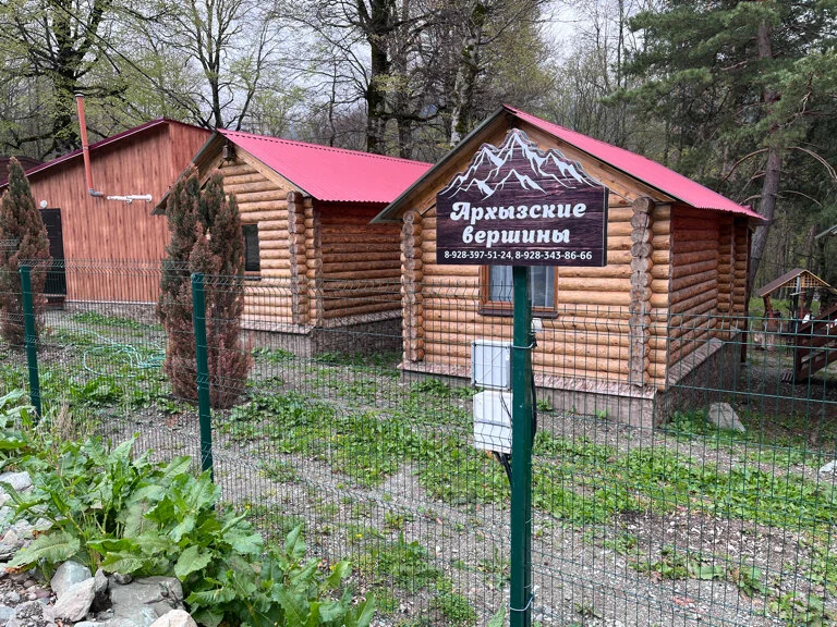 Изображение вывески с контактами на фоне деревянных домиков